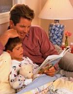 Obrázek otec poslouchal jeho syn četl knihu před spaním