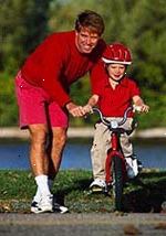 Obrázek otec učí svého malého syna, jak se jezdí na kole