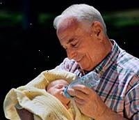 Obrázek dědeček drží jeho novorozeného vnuka, krmení mu láhev